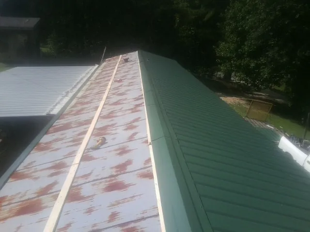 Old rusted panels beside newly installed green metal roofing — Wind Damage Roof Repair by Roofing Brothers in Stone Harbor
