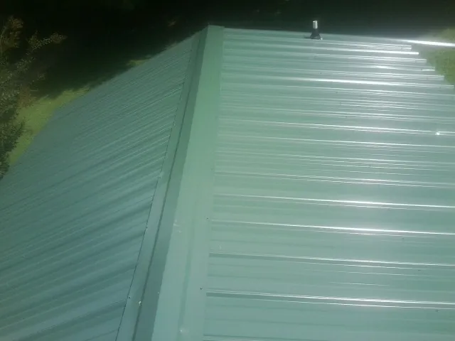 New green metal panels meeting at the ridge of a roof — Flat Roof Repair work by our crew in Stone Harbor
