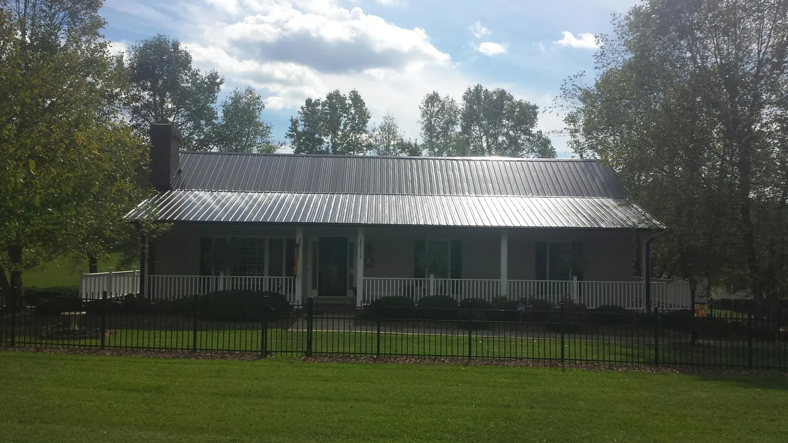 Gray metal roof on a brick ranch with a full width front porch — Gutter Guard Installation work by our crew in Stone Harbor