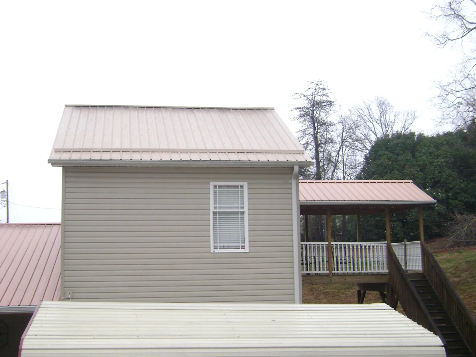 Tan metal roofs on a two story addition and attached porch, from a Roof Replacement job in Stone Harbor