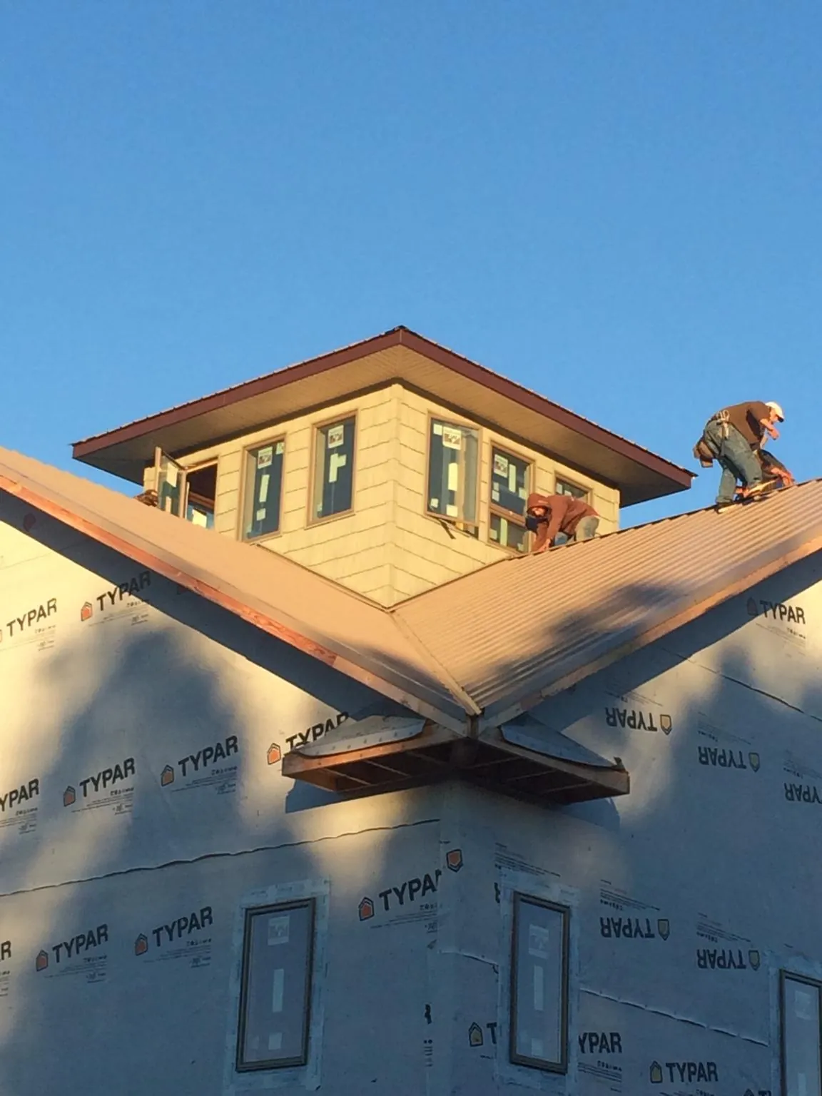 Roofers working around a rooftop cupola on a new metal roof at sunset — Roof Waterproofing in Stone Harbor by Roofing Brothers